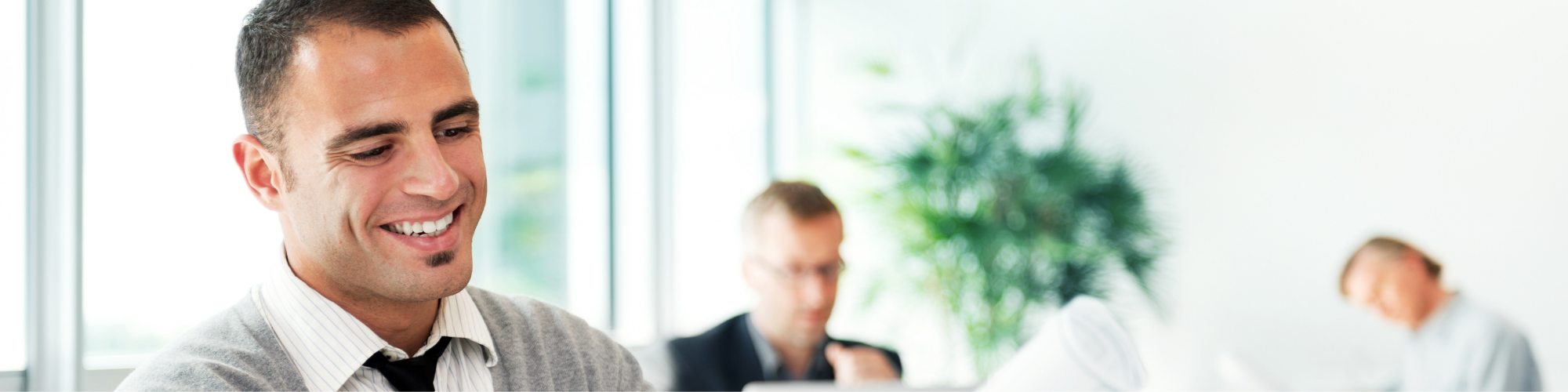 man in an office setting smiling and reviewing paperwork 